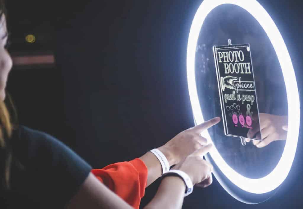 doigt appuyant sur un écran tactile d'un photobooth ringlight éclairé