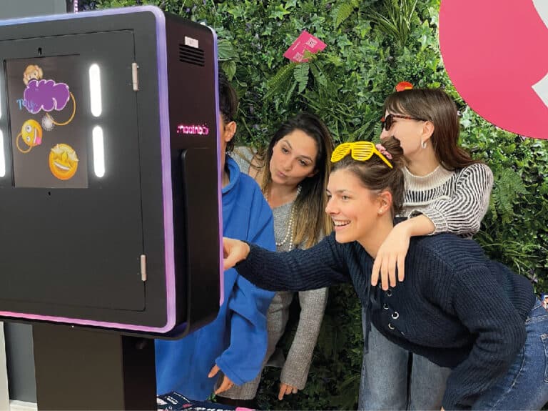 groupe de femme se prenant en photos grâce à une borne photo shootnbox photo booth mur végetal avec lunettes rétro