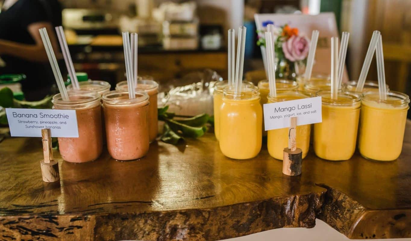smoothie banane mangue avec paille dans bocal en verre sur table en bois artisanale