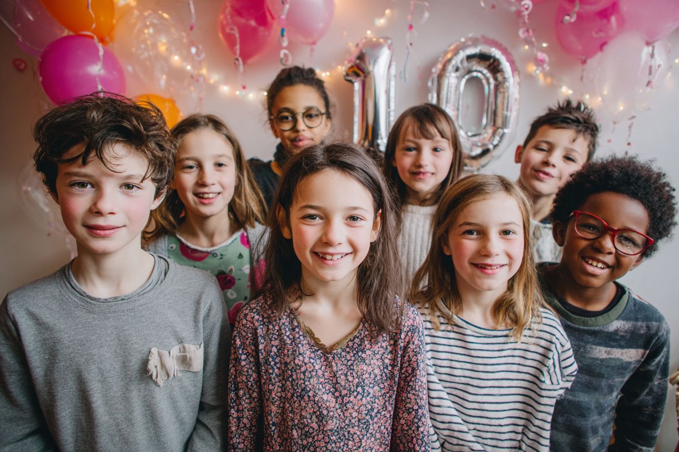 Anniversaire 10 ans à la maison avec photobooth : enfants rient, ballon chiffre 10, guirlandes et gâteau.