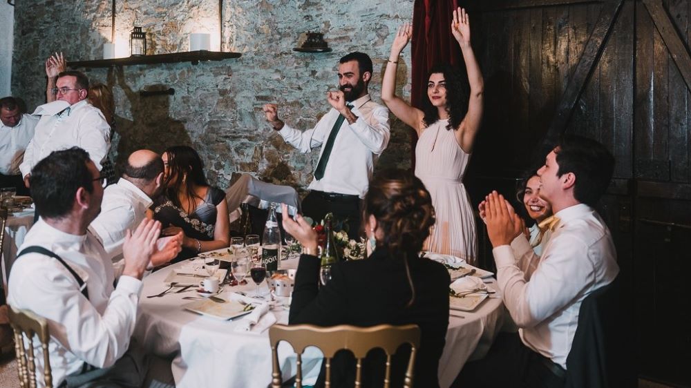 table diner de mariage avec invités assis et debout chemise blanche repas