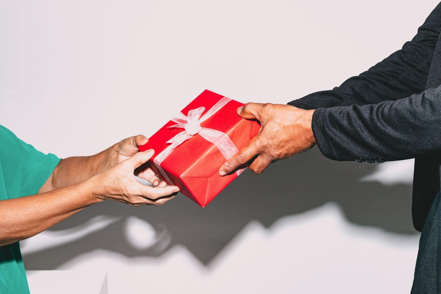 paquet cadeau rouge noeud blanc couple homme femme zoom mains échange offrir