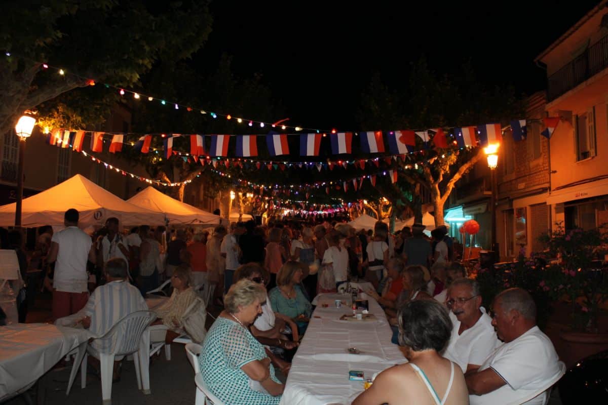 soirée fête de village nuit sans étoile habitants locaux qui dine grande tablée guirlande drapeau français extérieur dehors