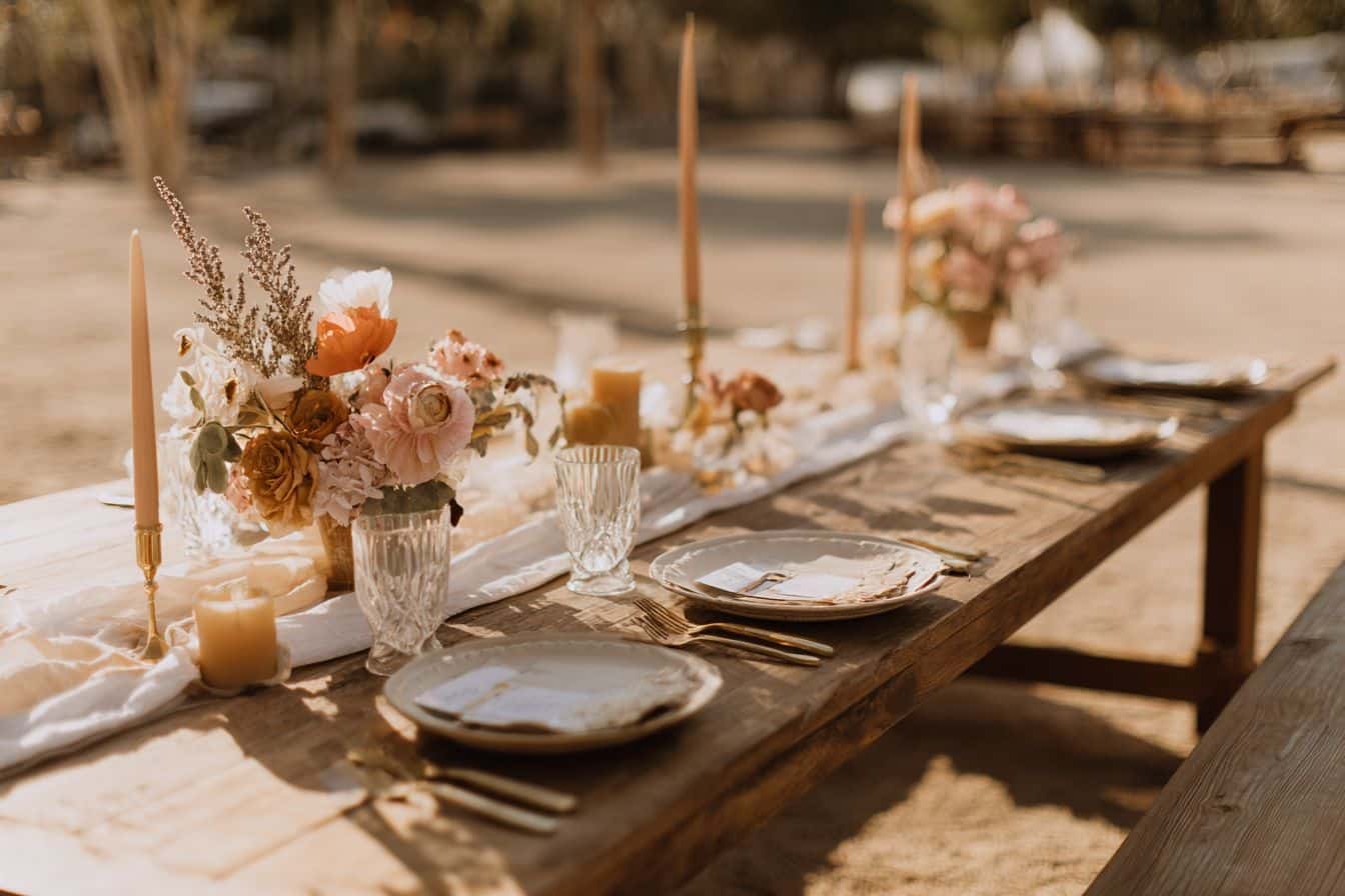 Table de réception de mariage décorée avec des fleurs locales, bougies en cire naturelle et vaisselle en céramique, ambiance champêtre chic.