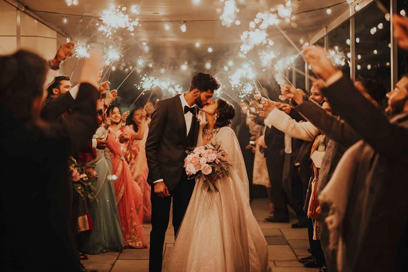 Entrée romantique des mariés dans la salle de réception, main dans la main, sous une allée de cierges magiques tenue par les invités.