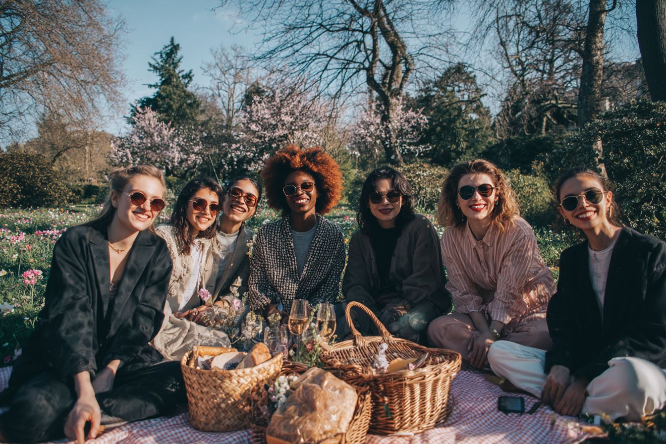 EVJF pas cher entre copines en France, jeunes femmes d’origines diverses partageant un pique-nique en plein air, ambiance festive et conviviale.