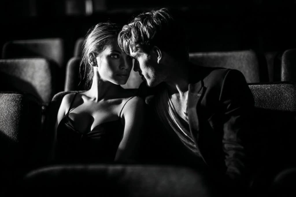 Portrait artistique en noir et blanc d’un couple dans un décor vintage de cinéma.